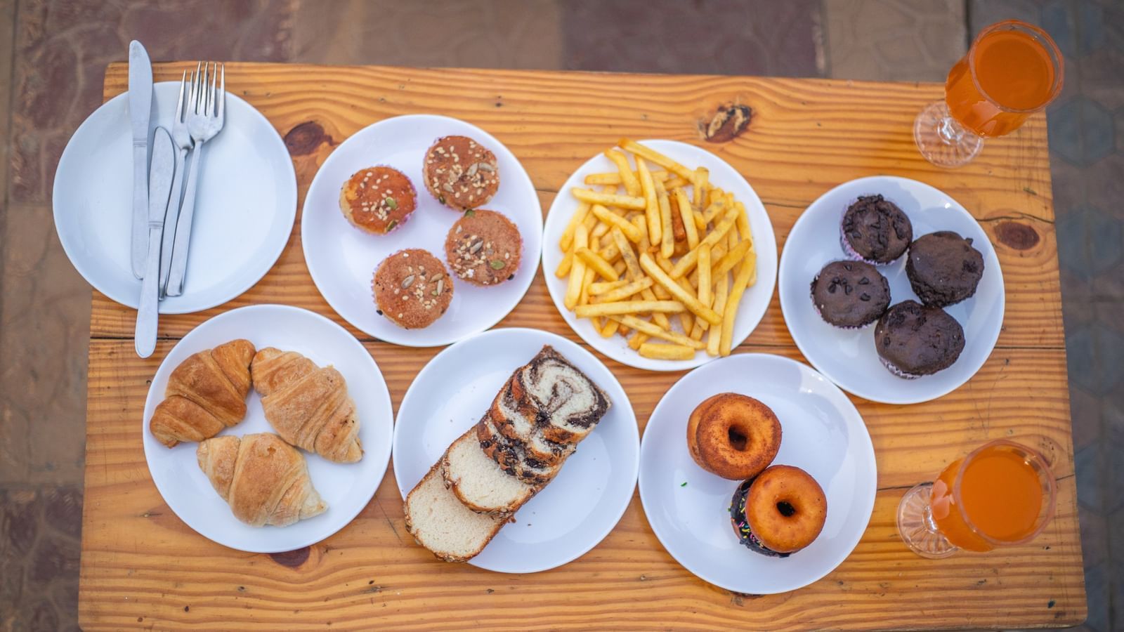 An overhead shot of a wooden platter with various snacks including chips, samosas, and 2 doughnuts, at Daksh Resort & Amusement Park, Sasan Gir.