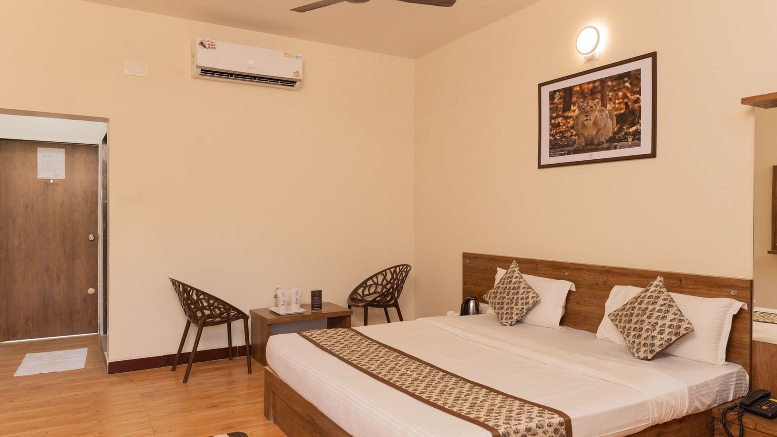 An elegant room with a double bed, chairs, and wall-mounted artwork at Daksh Resort & Amusement Park.