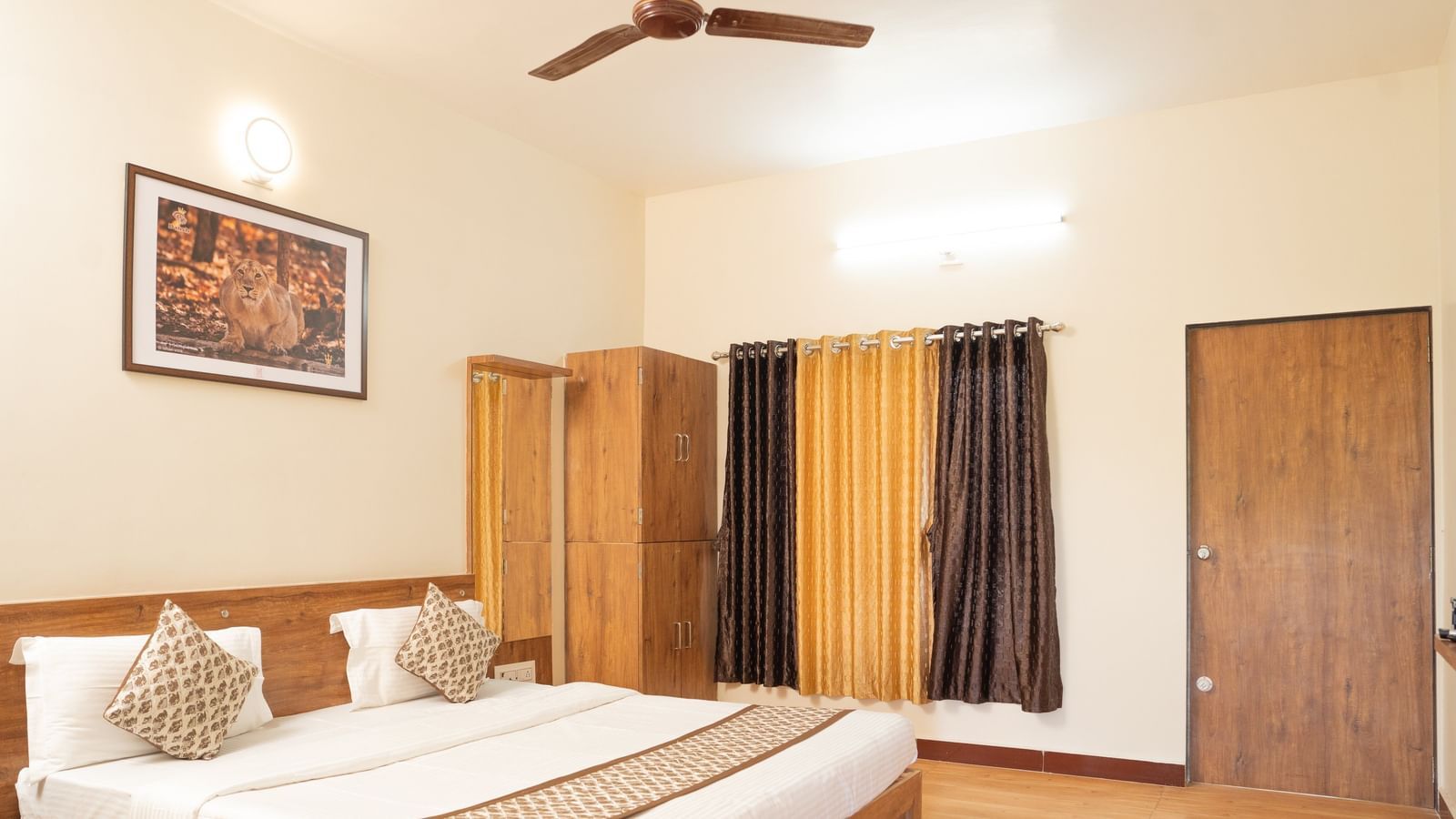 A guest room with a double bed, wooden furniture, and ceiling fan at Daksh Resort & Amusement Park.