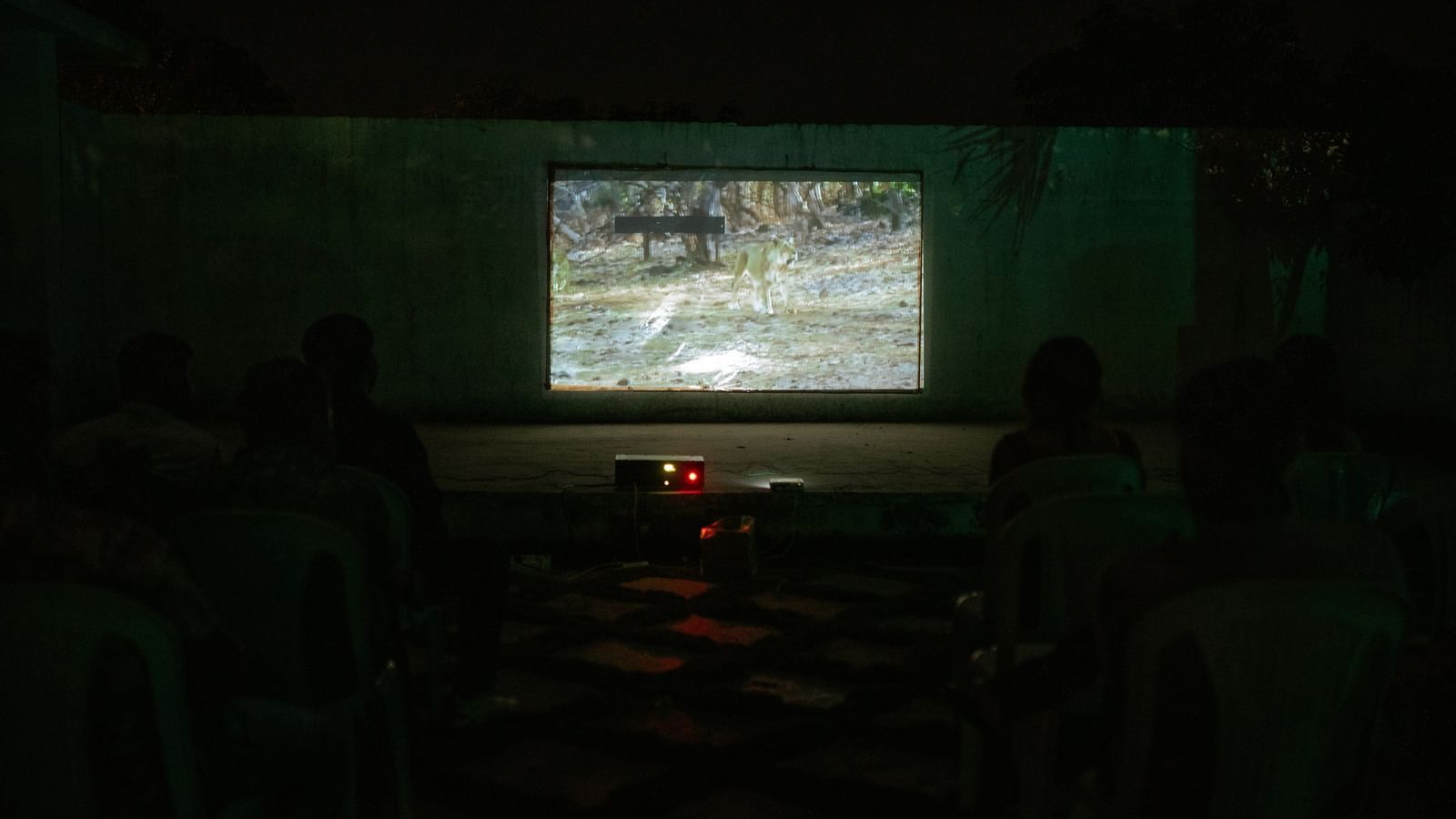 An outdoor theatre setting featuring a film screening on a projector screen with chairs arranged in front at Daksh Resort and Amusement Park.