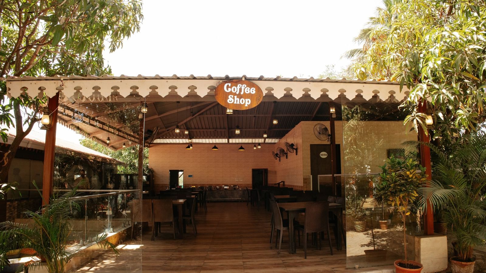 An open-air dining area with wooden seating and a rustic roof, surrounded by greenery at Daksh Resort and Amusement Park. 