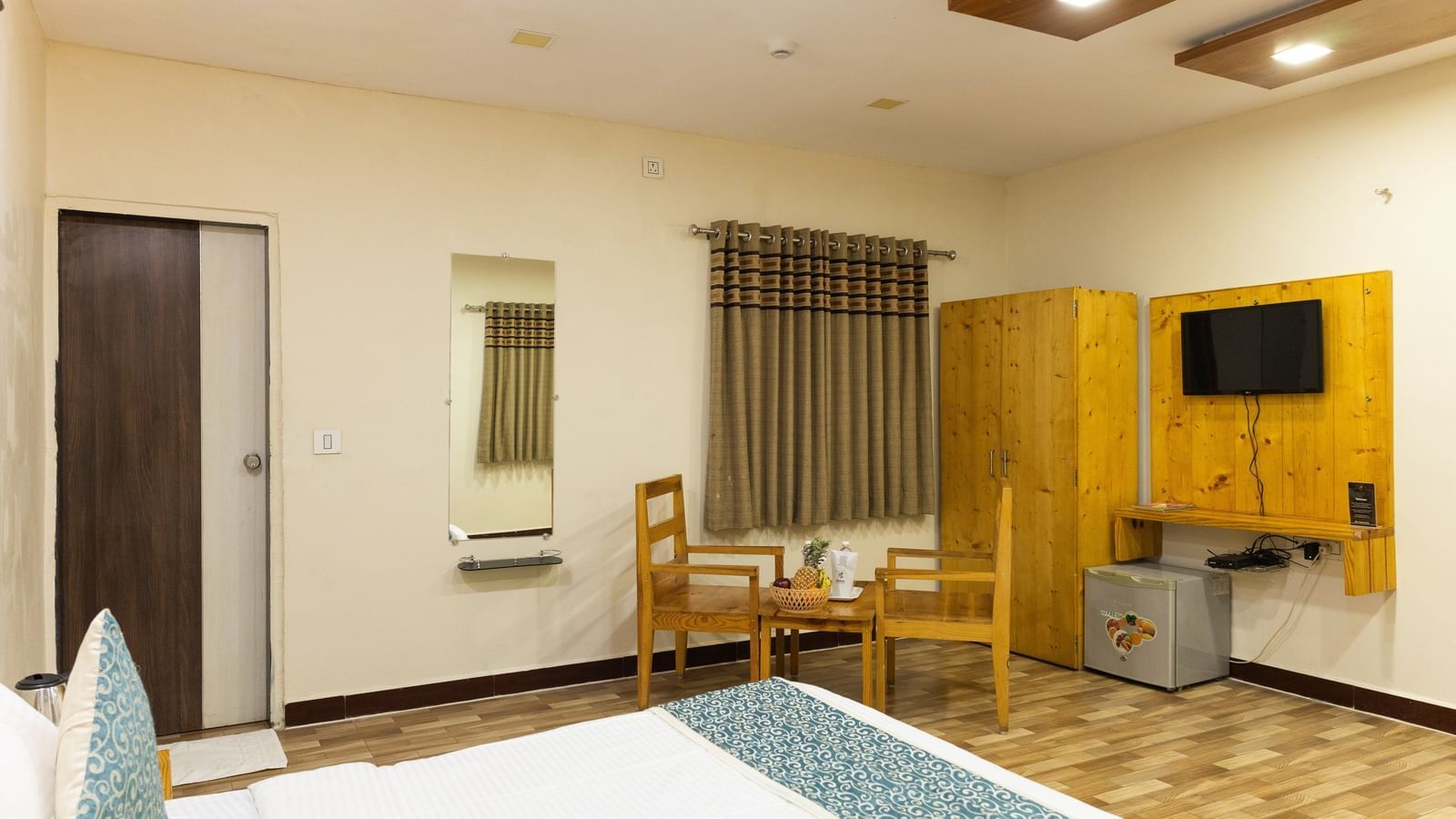 A room with a bed, a dining set, and a wardrobe near a curtained window at Daksh Resort & Amusement Park.