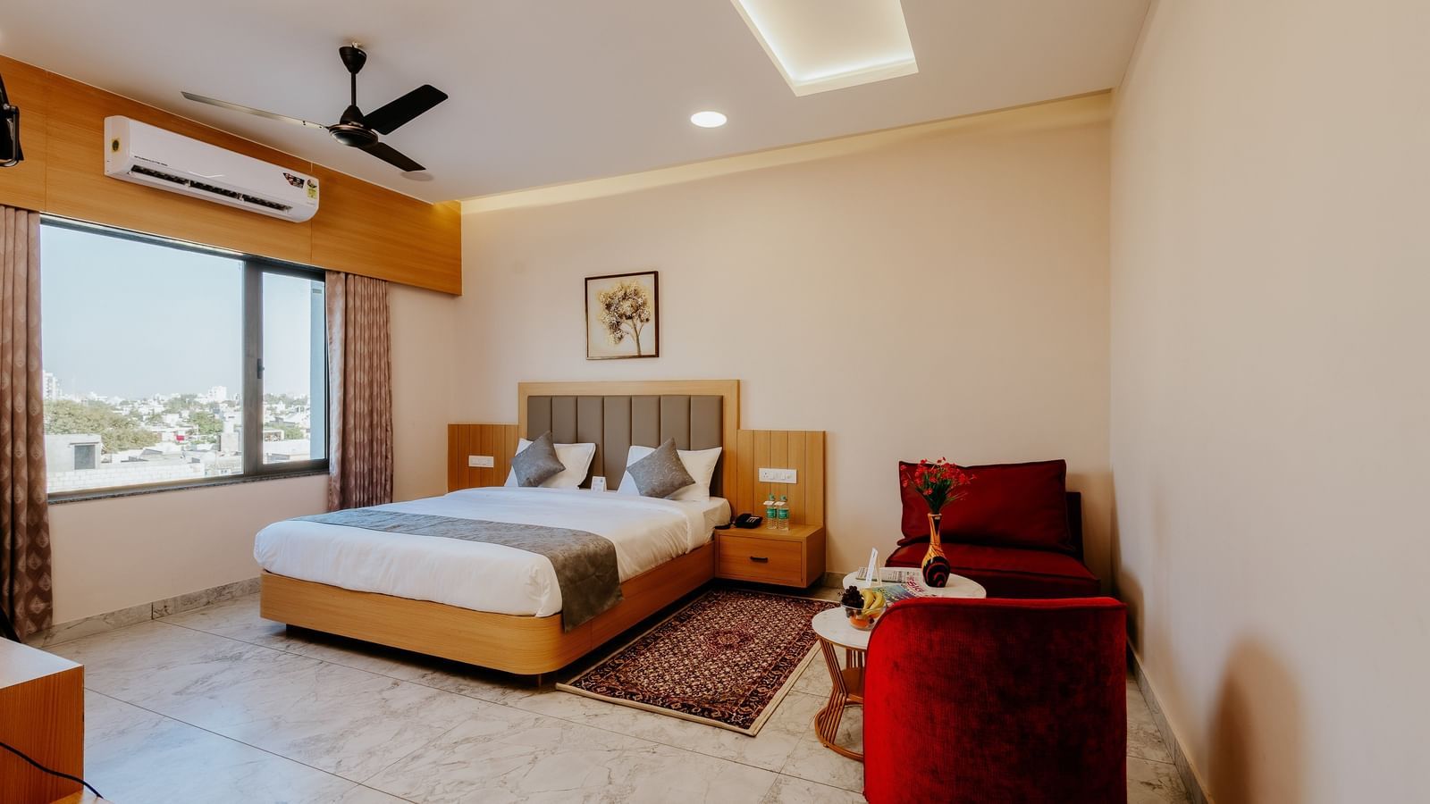A bright and airy bedroom at Daksh The Grand Gowardhan, Dwarka, with a double bed, a common seating area, and ample natural light coming from the huge window.