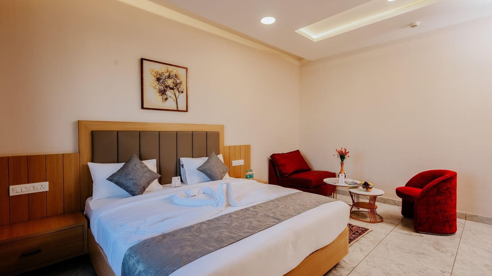 Corner view of an elegant bedroom at Daksh The Grand Gowardhan, Dwarka, with a neatly made double bed and a comfortable seating area.