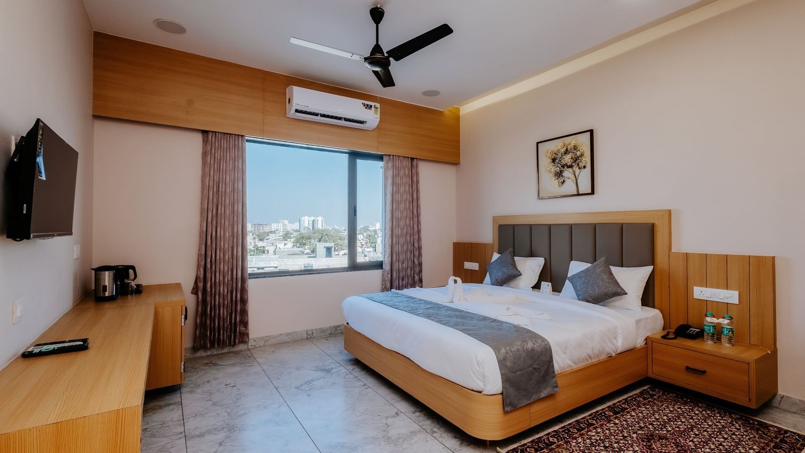 A well-appointed bedroom at Daksh The Grand Gowardhan, Dwarka, featuring a comfortable double bed, television, and window featuring views of the city.