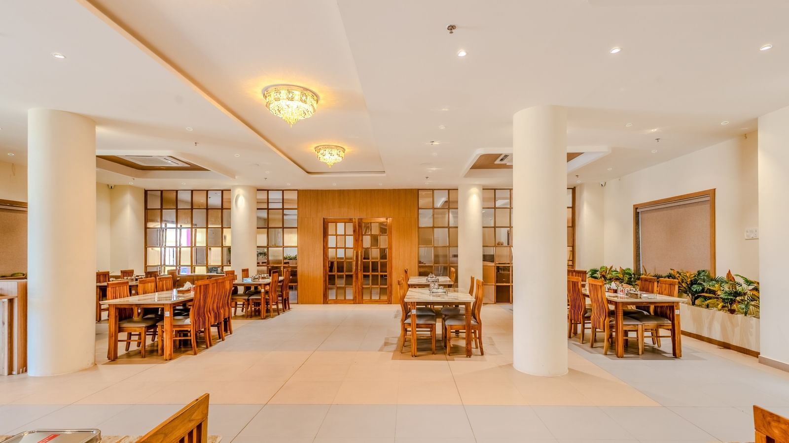 An elegant dining space at Daksh The Grand Gowardhan, Dwarka, with polished wooden furniture and ambient lighting.