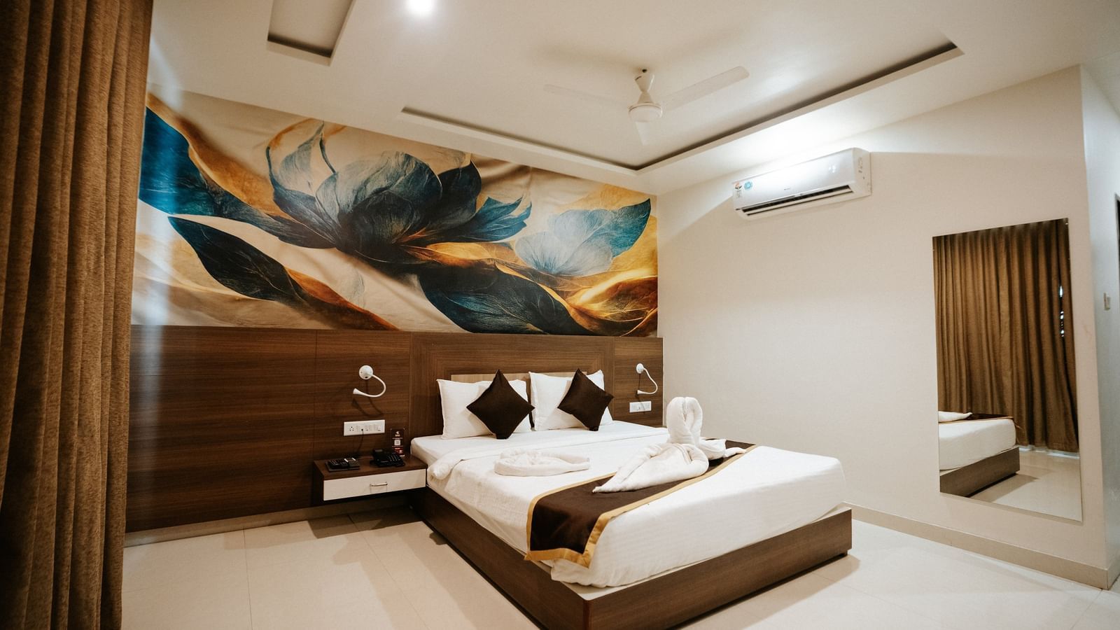 Detail of the room's media unit: wall-mounted TV, white desk, storage drawers, and a black office chair in a corner at Daksh The Madhuvan Suites, Dwarka.