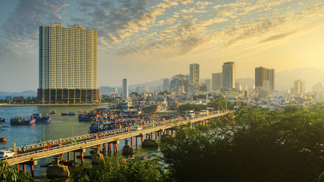An overview of Nha Trang with a bridge, a waterbody and buildings covered in fog seen.