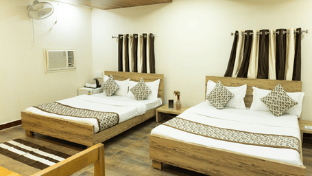 A room with two double beds, patterned cushions and wooden interiors at Daksh Resort & Amusement Park, Sasan Gir.