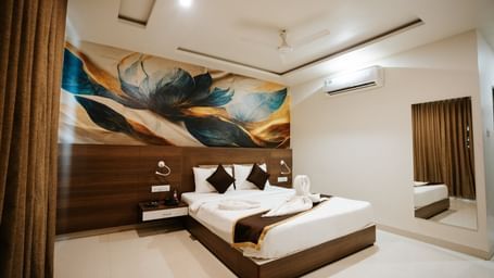 Detail of the room's media unit: wall-mounted TV, white desk, storage drawers, and a black office chair in a corner at Daksh The Madhuvan Suites, Dwarka.