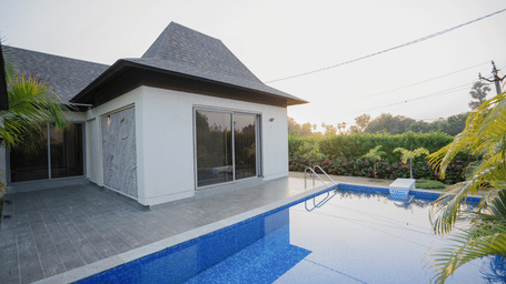 The exterior of a private villa showing a clean, blue swimming pool and modern white architecture - Daksh The Nirvana Retreat, Pavagadh