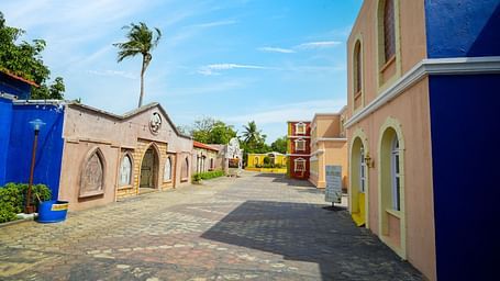 A cobblestone street inside MGM Dizzee World lined with pastel-colored, European-style buildings, offering a unique and picturesque walking experience.