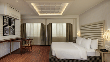Terrace Suite at Shilton Suites, Bengaluru, featuring twin beds, work desk, seating area, and large windows.