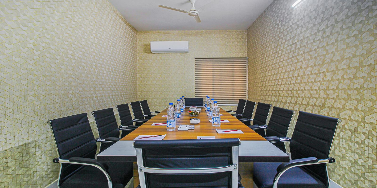 A conference room with a professional setting, featuring a large meeting table with water bottles and notepads for attendees.