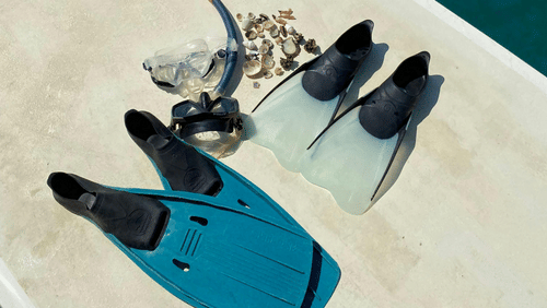 A pair of flippers, a pair of snorkels and a pair of fins on a boat.