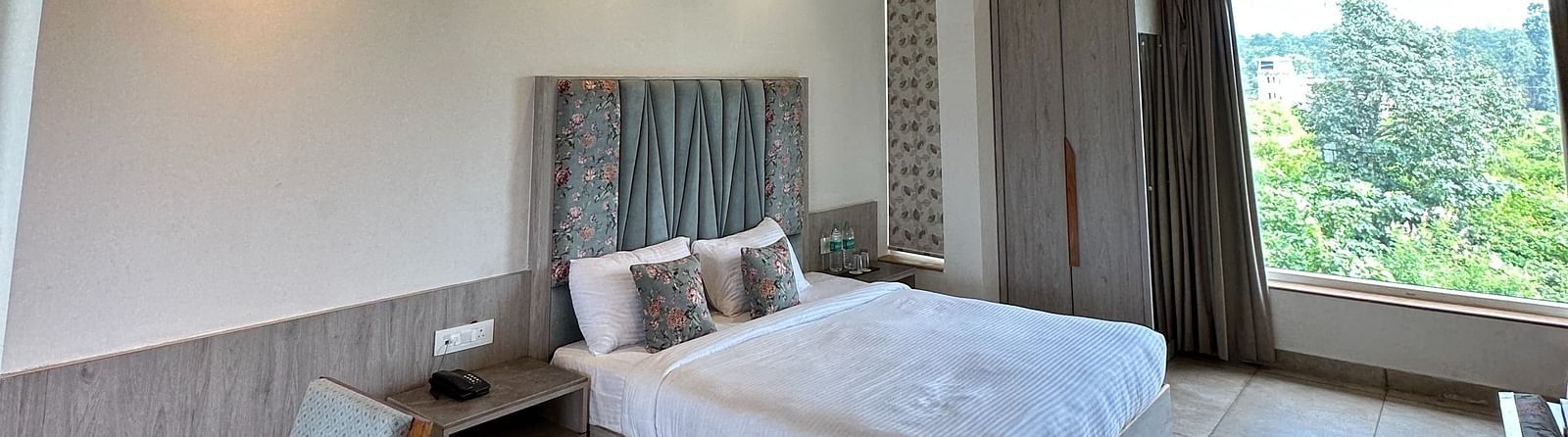 A modern hotel room with a king size bed, a wooden ceiling, and a staircase leading to an upper level.