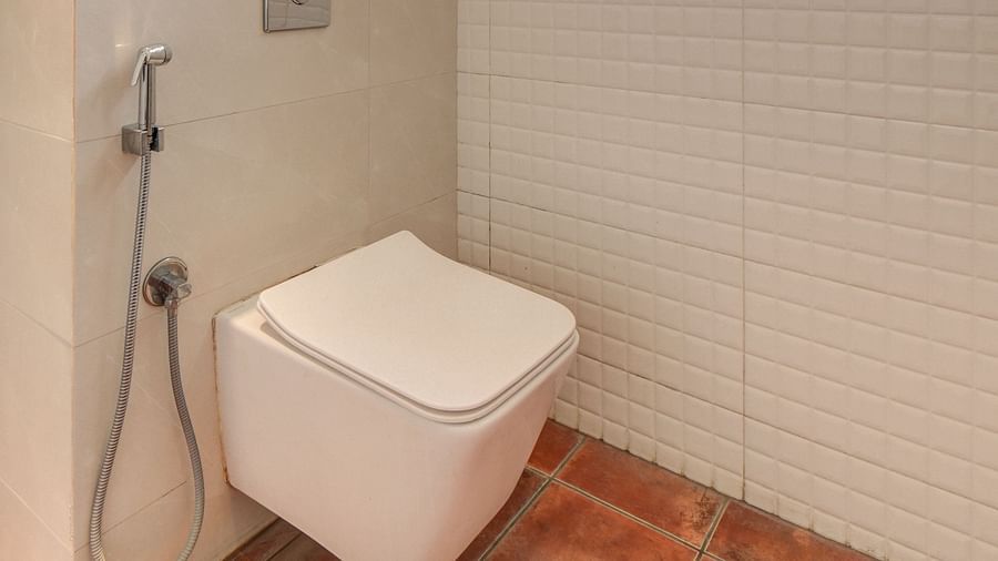 A spacious washroom with a western toilet and a window with frosted glass at Harigovinda's JNStay