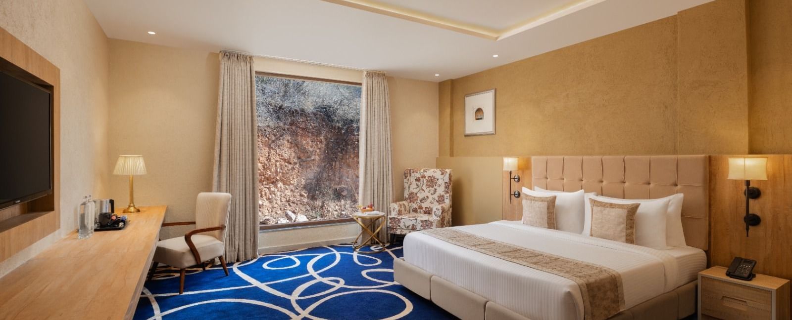 Superior room with king bed and blue accent rug at Essentia Luxury Resort & Spa, Udaipur.