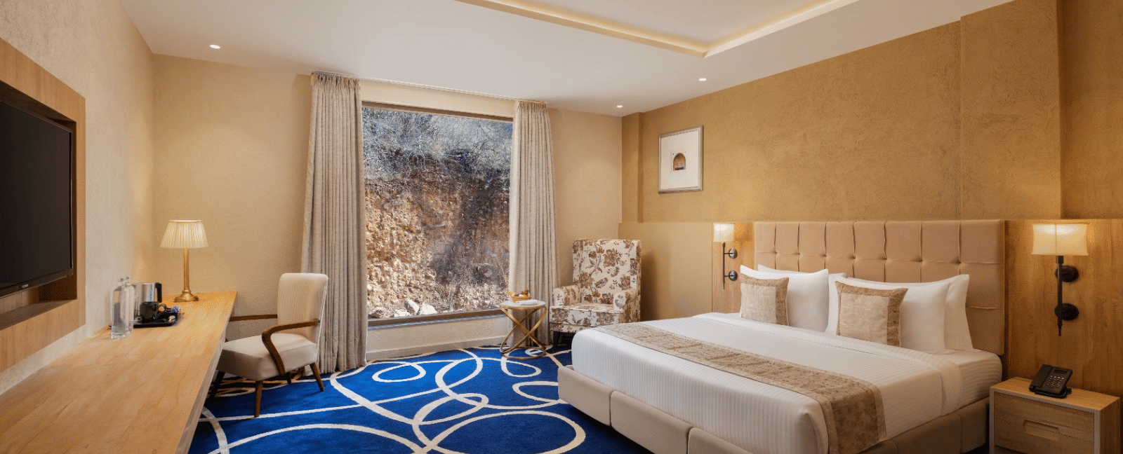 Superior room with king bed and blue accent rug at Essentia Luxury Resort & Spa, Udaipur.