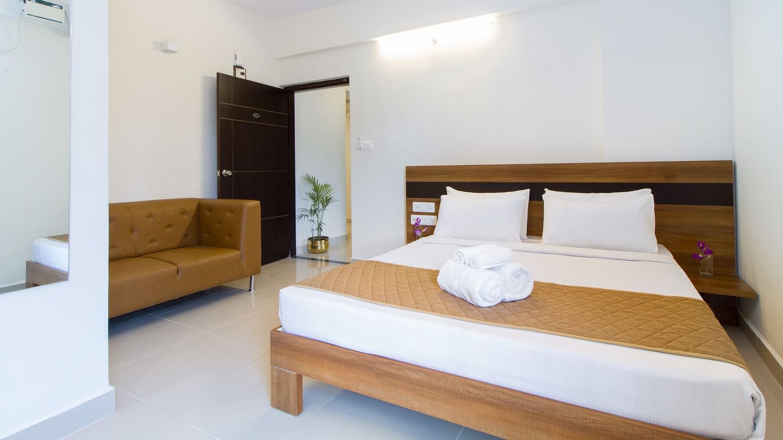 A hotel room including a double bed with bedding and an armchair at Sanctum Suites Whitefield, Bangalore.