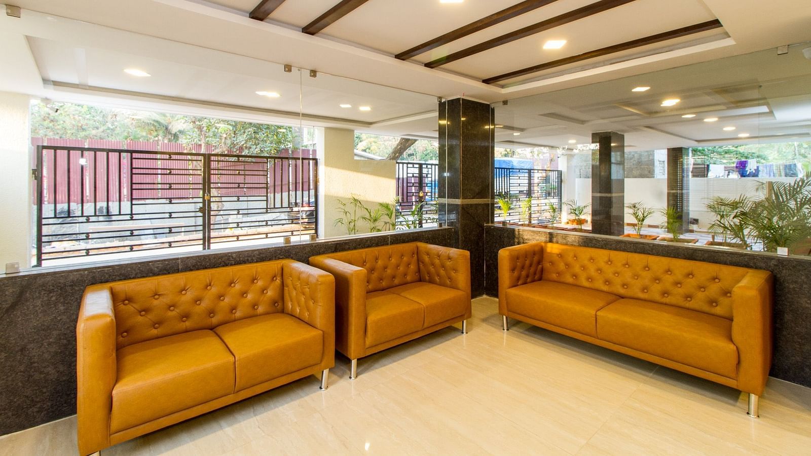 A lobby showing two mustard-coloured sofas and large windows at Sanctum Suites Whitefield, Bangalore.