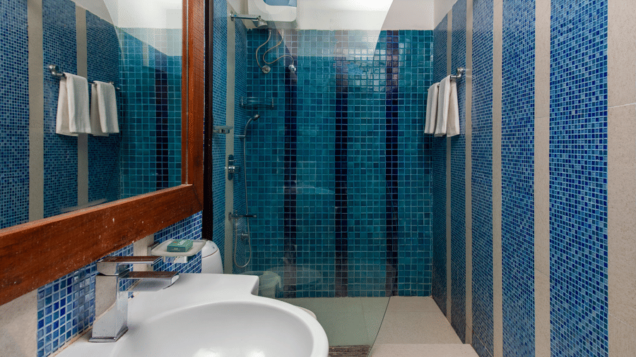  Bathroom with a white washbasin, blue tiled shower enclosure and wooden-framed mirror.