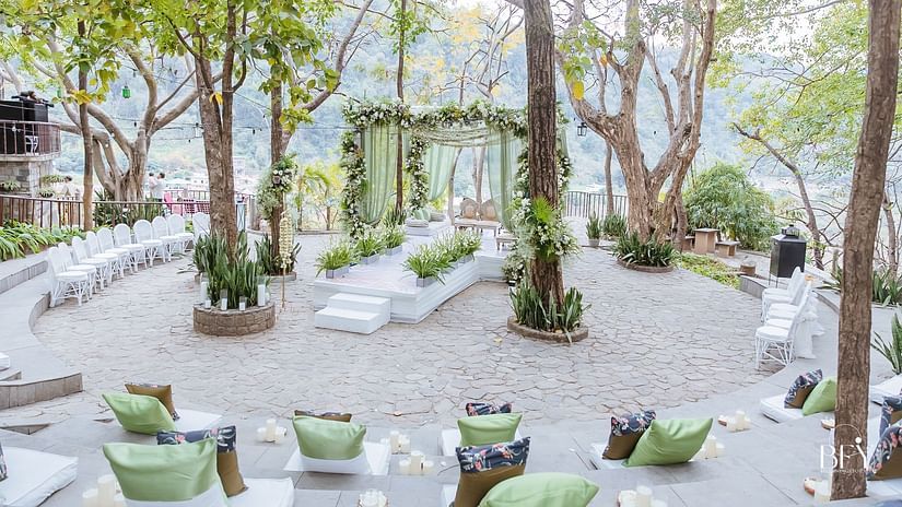 Outdoor seating arrangement surrounded by lush trees for a wedding event
