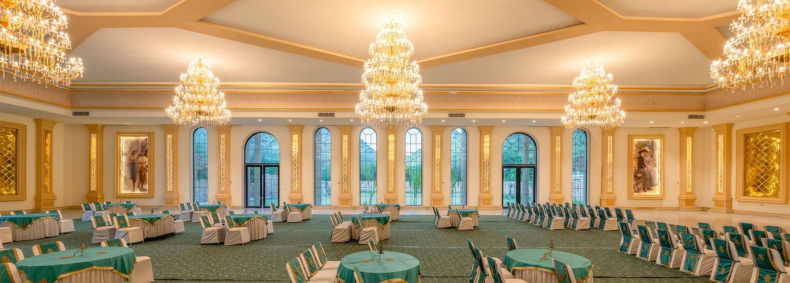 Side view of a banquet hall featuring round tables with chairs and chandeliers elegantly hanging from the ceiling at Valley by Grassfield.