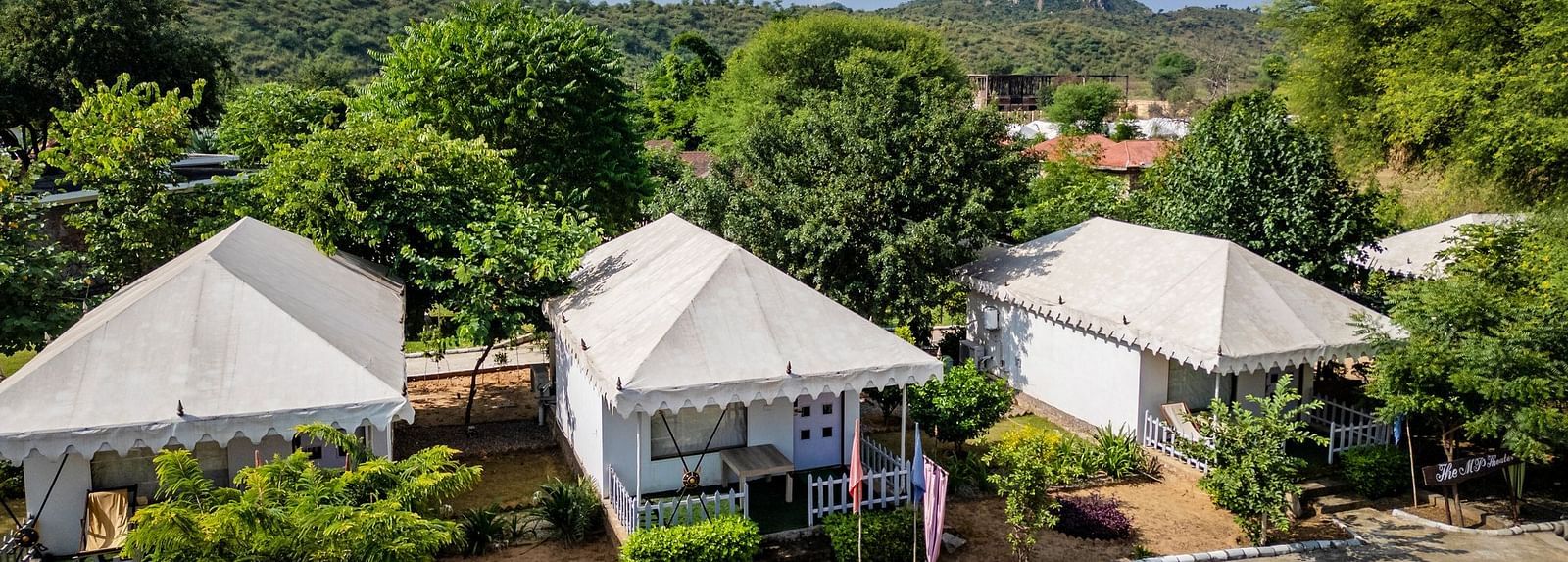 Aerial view of tent-style accommodations at Valley by Grassfield, nestled amidst lush trees and greenery.