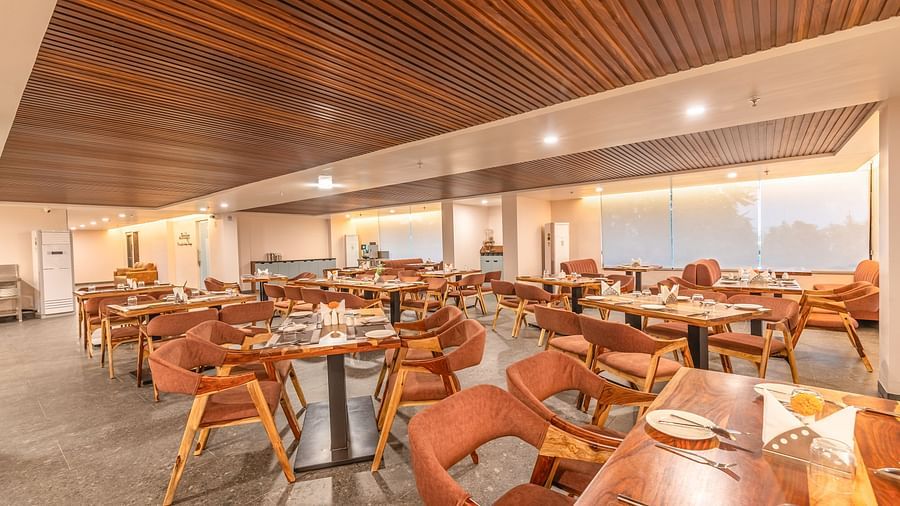Interior of The Bridge restaurant at Clarks Inn Suite Jaipur featuring tables and chairs arranged with a view of the outside through large windows
