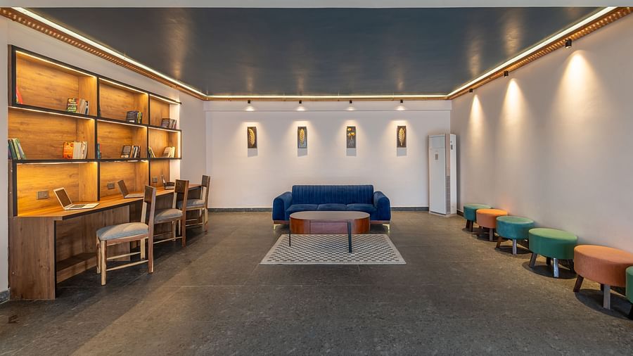 Lobby area of Clarks Inn Suites jaipur featuring sitting spaces with sofas and ottomans and a dedicated workstation with laptops on a desk and chairs