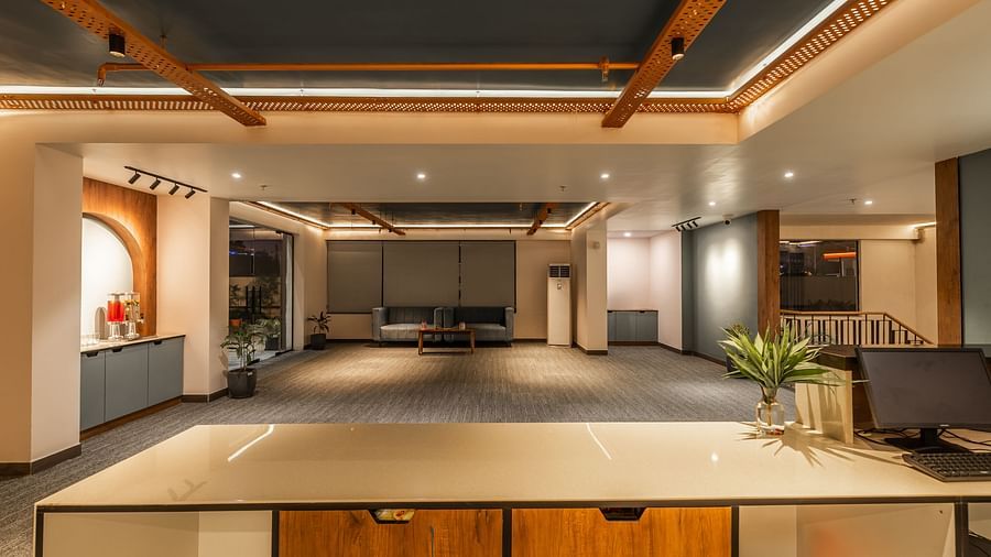 The reception desk of Clarks Inn Suites Jaipur, Ajmer Road with a monitor on it next to a plant and in front of it are two couches with a centre table