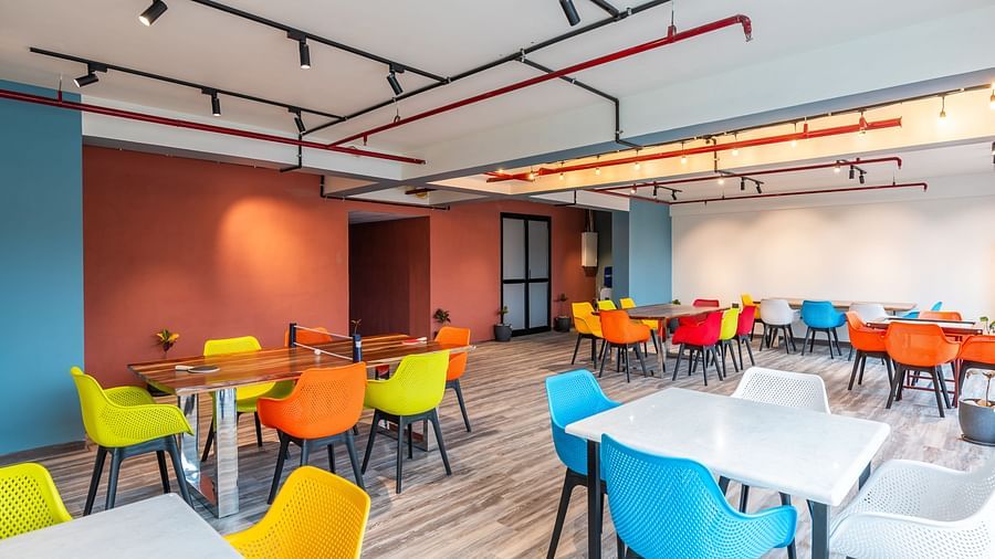 Game room at Clarks Inn Suites Jaipur, Ajmer Road features a table tennis surrounded by colourful chairs and a carrom board in the distance.
