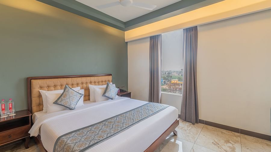 Deluxe King Room at Clarks Inn Suites Jaipur featuring  featuring a plush king size bed, stylish decor, warm lighting, large windows, elegant curtains, and a relaxing atmosphere