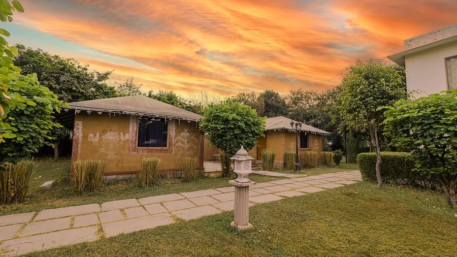 A view of cottages at Clarks Inn Suites, Ranthambore with a dramatic sunset in the background.