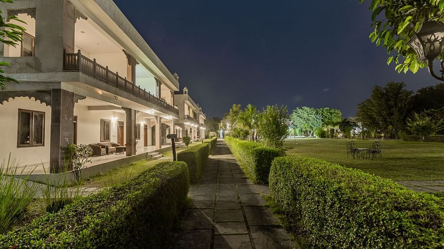 A view of the resort buildings at Clarks Inn Suites, Ranthambore illuminated at night.
