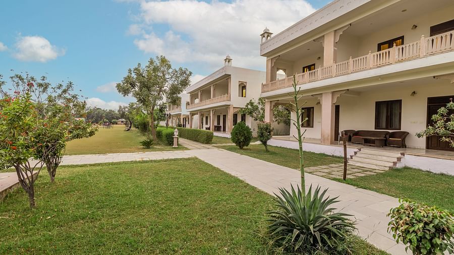 A view of the resort grounds at Clarks Inn Suites, Ranthambore with well-maintained lawns and a walkway leading to the guest rooms.