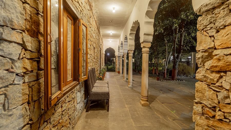 A stone walled corridor at Clarks Inn Suites, Ranthambore with arched doorways leading to guest rooms.