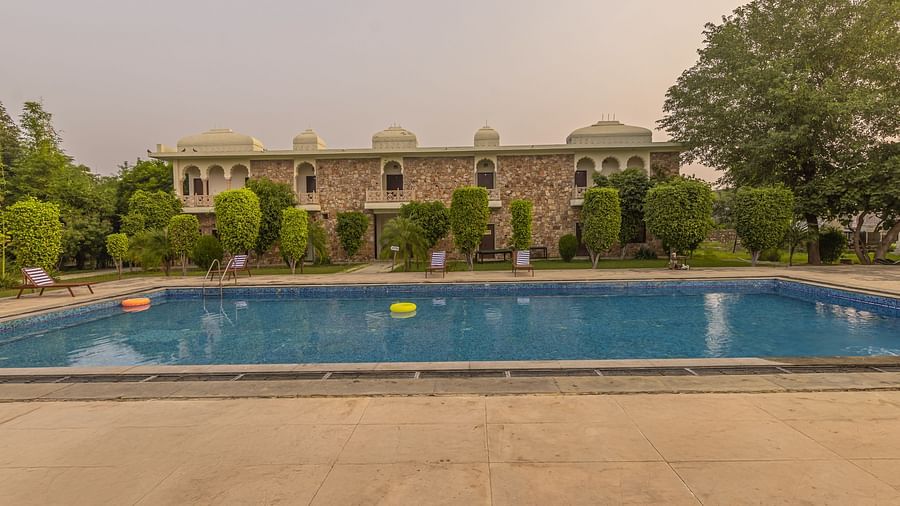 A swimming pool at Clarks Inn Suites, Ranthambore with the resort building in the background.