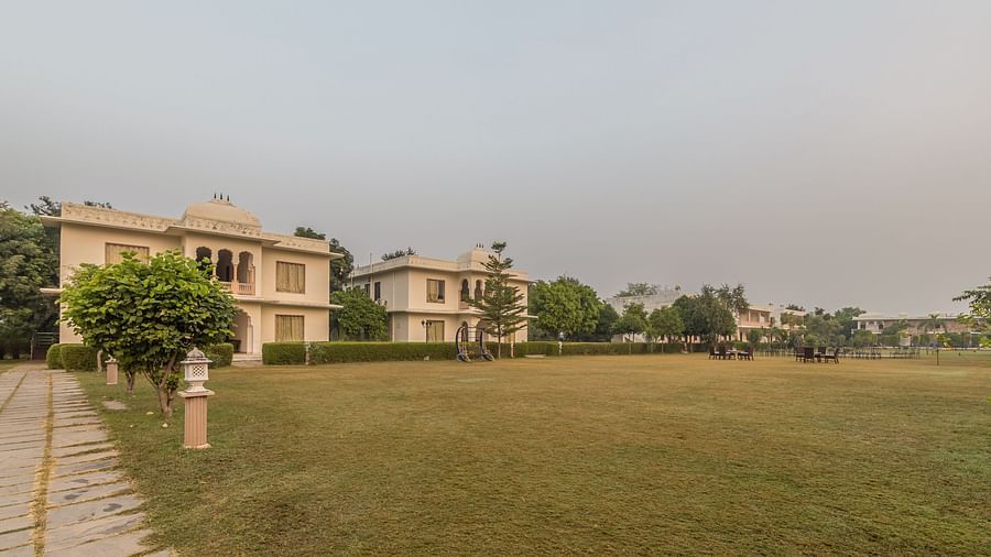 A view of the resort grounds at Clarks Inn Suites, Ranthambore with lush green lawns and the resort buildings in the background.