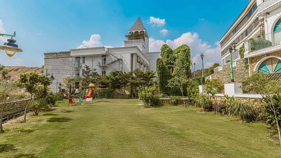 An image of a lawn and garden in front of a hotel building