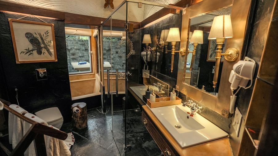 A dimly lit bathroom with a bathtub, sink, and mirror, wooden interior - The Den Corbett Resort & Spa, Kumeria.