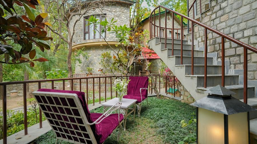 An outdoor patio with chairs and plants, stairs leading to a building - The Den Corbett Resort & Spa, Kumeria.