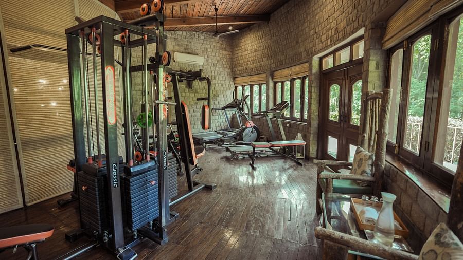 A gym with exercise equipment and large windows, interior setting.