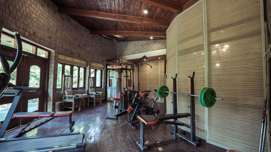 A gym with exercise equipment and large windows, interior setting.