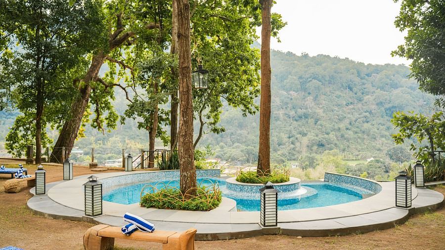 A patio with lounge chairs and a small pool feature, surrounded by tall trees.