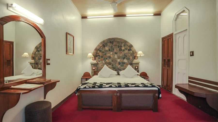 A bedroom with a bed, a rug, and warm lighting, interior setting - The Den Corbett Resort & Spa, Kumeria.