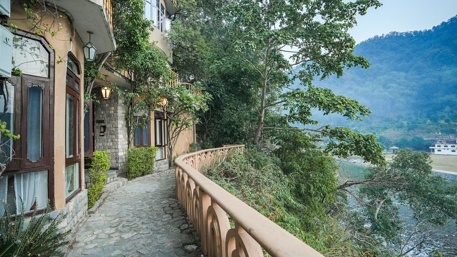 A narrow walkway with a railing overlooking a mountain landscape - The Den Corbett Resort & Spa, Kumeria.