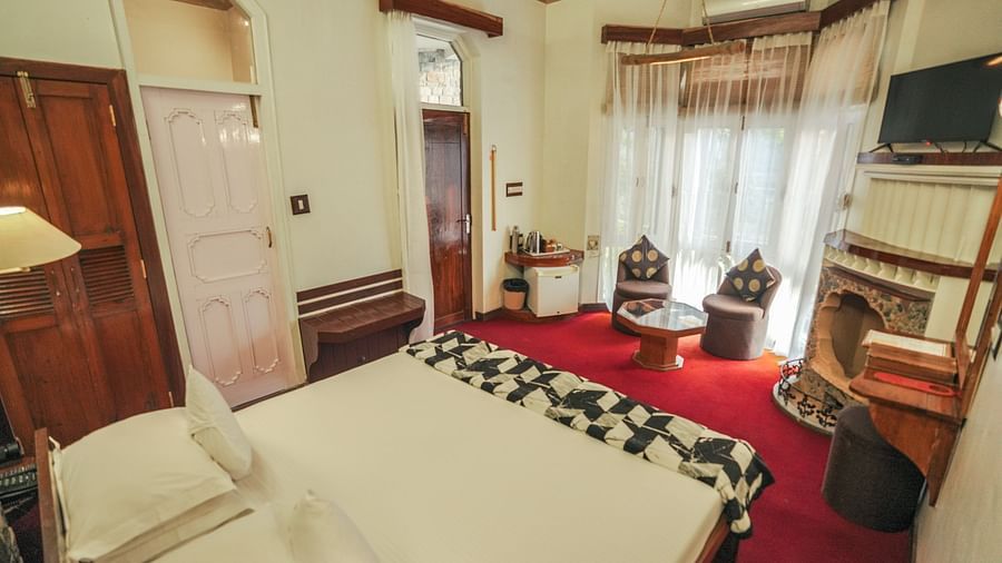 A bedroom with a bed, a rug, and warm lighting, interior setting - The Den Corbett Resort & Spa, Kumeria.