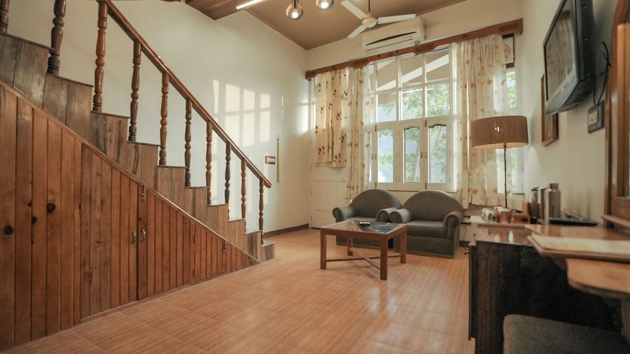 A living room with stairs, a couch, and a television, interior setting with wooden elements - The Den Corbett Resort & Spa, Kumeria.